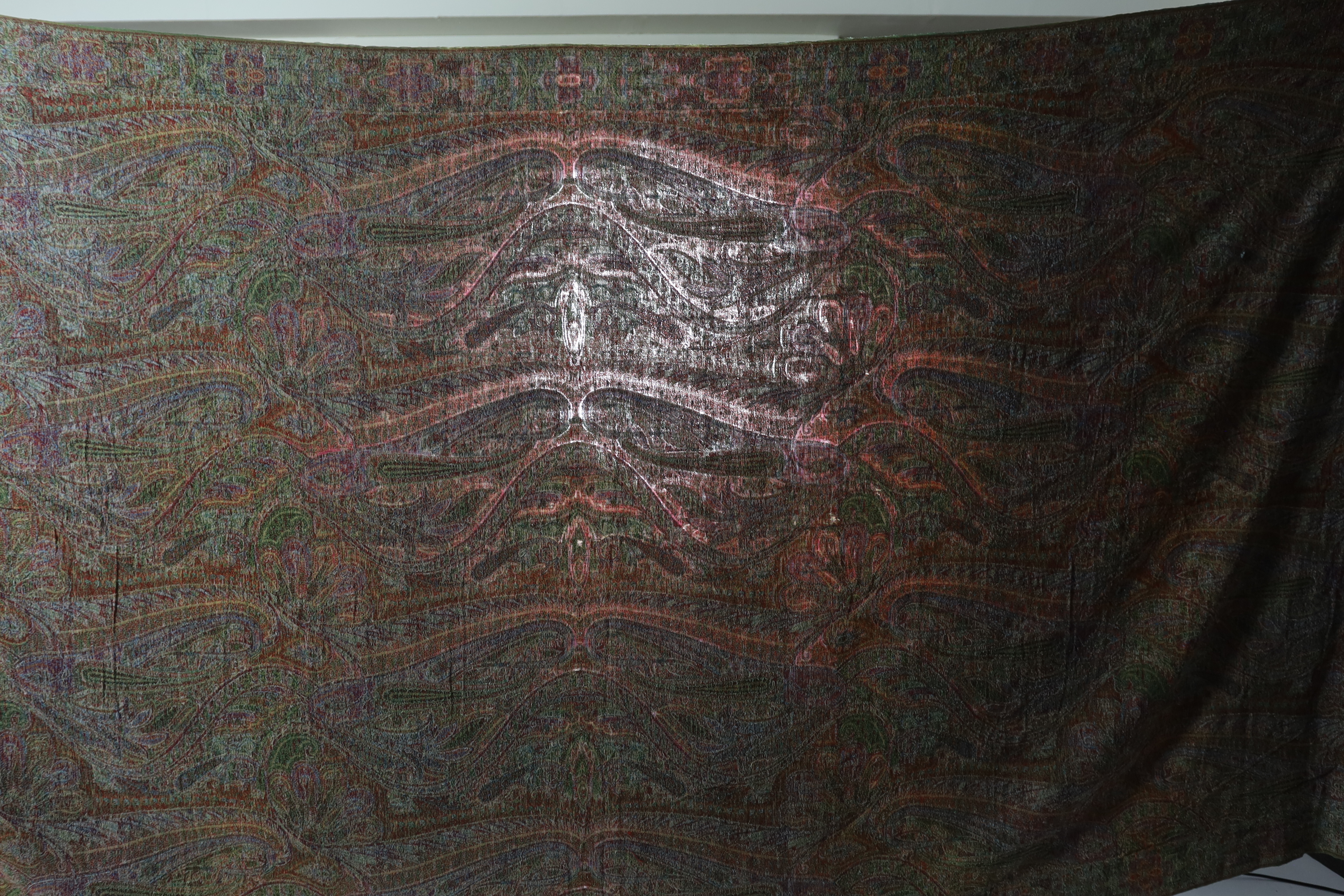 An 1860’s-70’s Scottish Paisley wool shawl, woven with multi coloured wools in a large scrolling teardrop design, bordered and fringed both ends 165cm wide x 345cm long